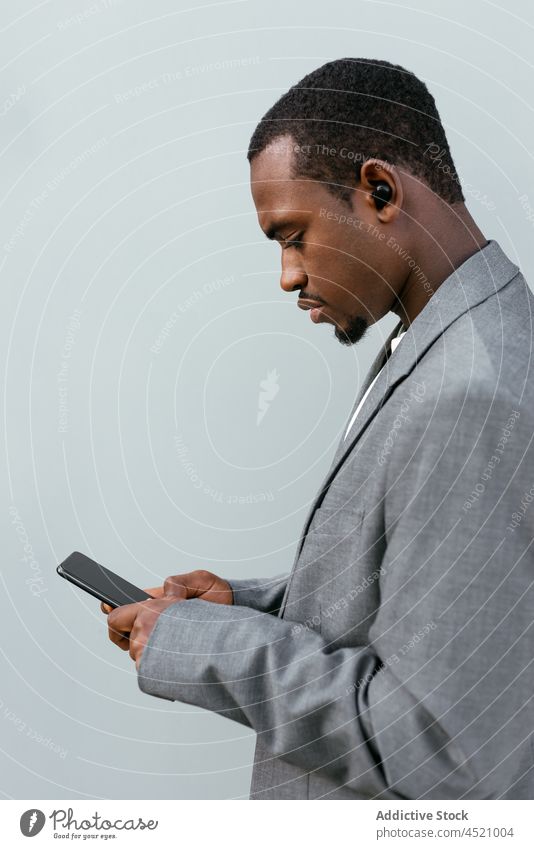 Black executive man browsing smartphone businessman using formal connection online suit listen music earbuds male device worker mobile entrepreneur black