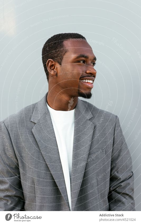 Positive black man in formal outfit standing near gray wall businessman positive elegant respectable portrait professional appearance style well dressed suit