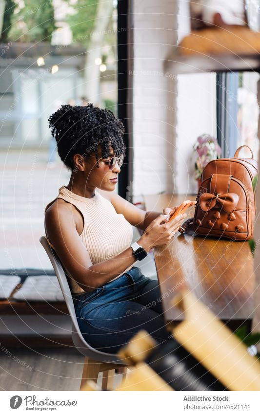 Serious stylish black lady using smartphone in cafe woman trendy confident communicate online free time message social media style internet female young ethnic