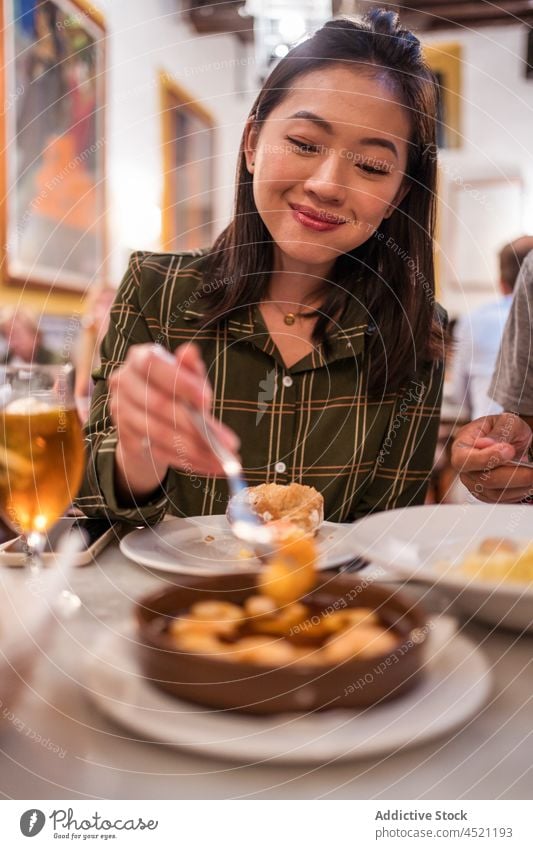 Happy young Asian woman eating shrimps in restaurant smile hungry delicious meal food content positive together female asian ethnic long hair dark hair casual