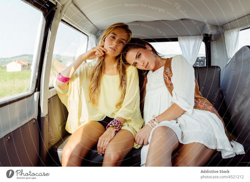 Happy girls sitting inside a van cute pretty young woman two couple friends friendship youth women caucasian summer summertime caravan summer clothes colorful