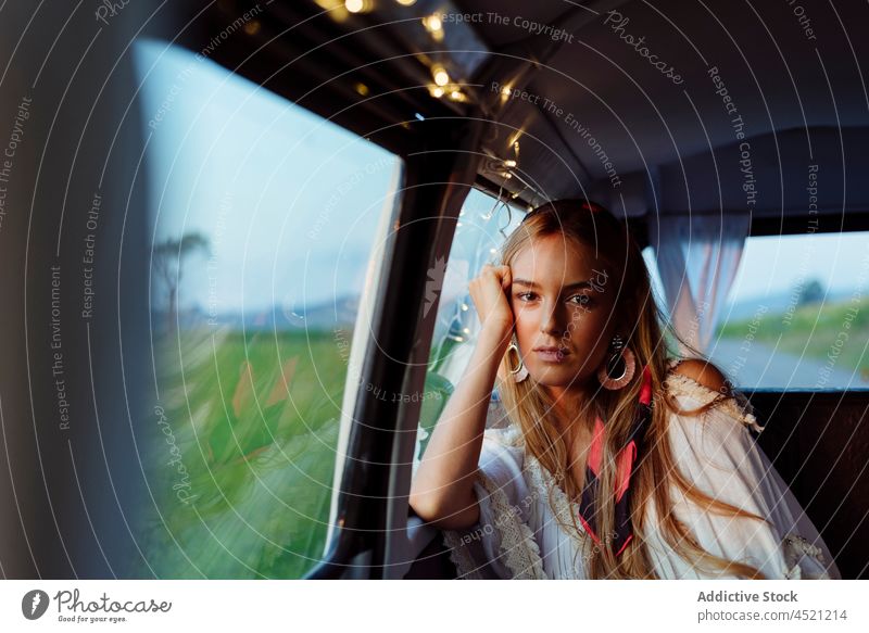 Confident beautiful blonde girl inside a vintage van looking at the camera pretty cute woman caucasian leaning window caravan garland tanned sunset leisure
