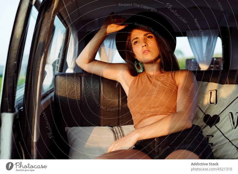 Attractive brunette girl inside a vintage van and sitting on the seat on a sunny day attractive sensual pretty woman female hat caucasian lying relaxed