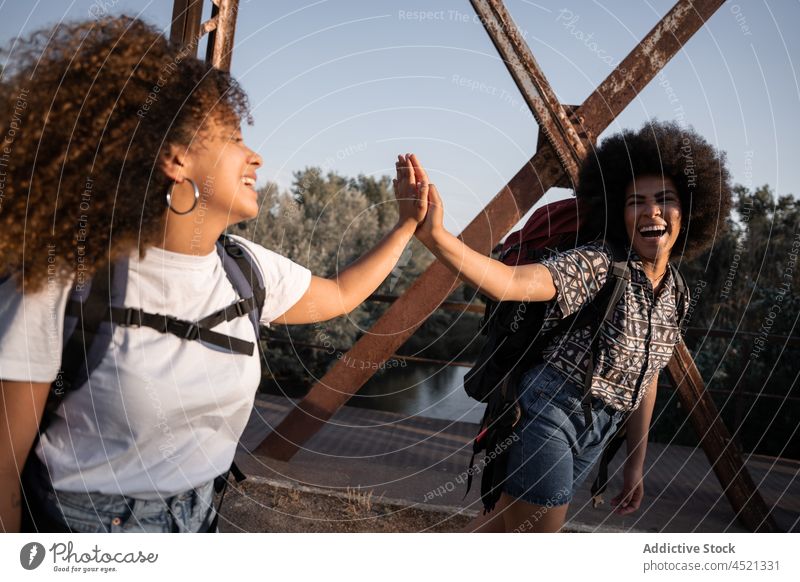 Cheerful black women giving high five on bridge hiker give laugh happy fun friendship adventure female best friend girlfriend carefree positive expressive