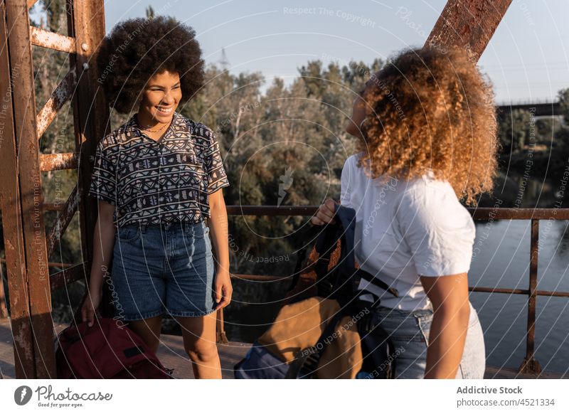 Black women doing halt on bridge during hiking trip friend hiker break weathered recreation positive adventure female rest shabby old traveler long hair