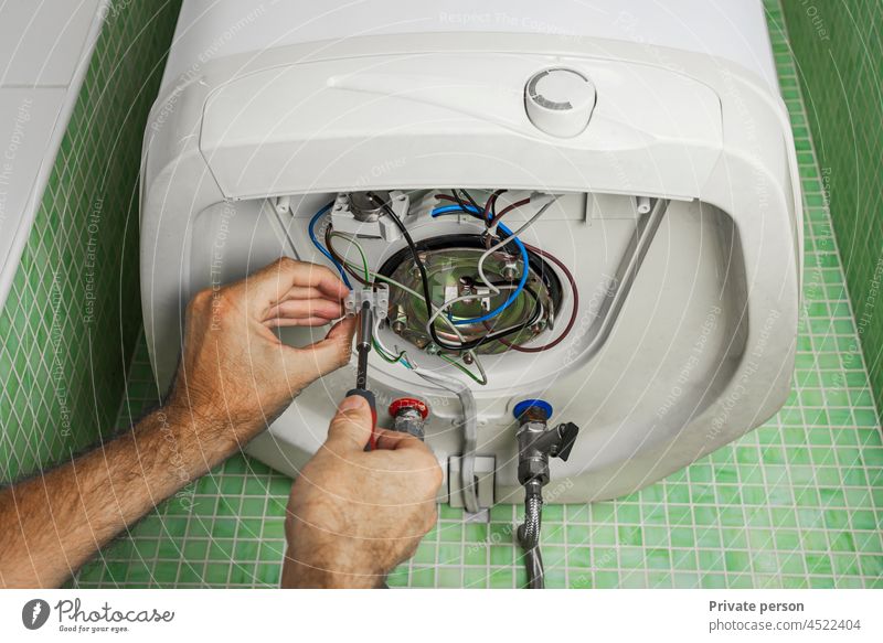 Water heater or boiler repair, with electrical wires and pipes in the bathroom. close-up. Repair electrician power connection screwdriver safety White Boiler