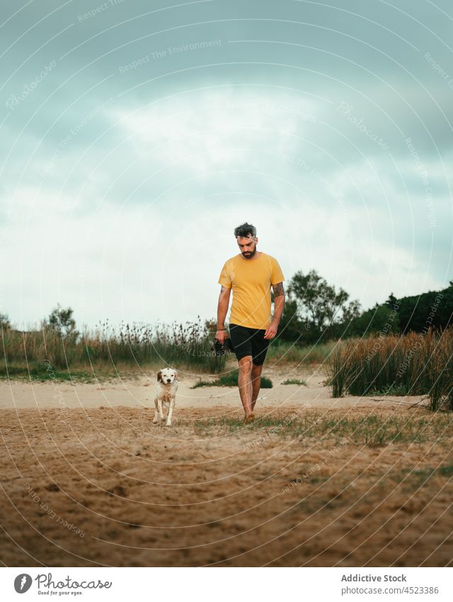 Man walking with dog on coast man owner animal shore pet nature beach domestic riverside canine mammal summer pedigree creature environment waterfront sand