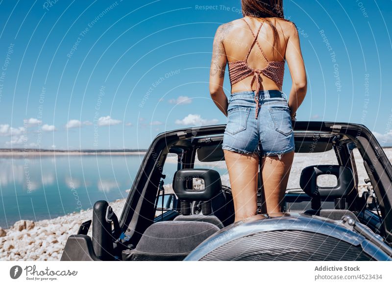 Anonymous trendy lady standing in cabriolet and admiring sea woman admire seascape car convertible road trip traveler beach vacation nature journey female young