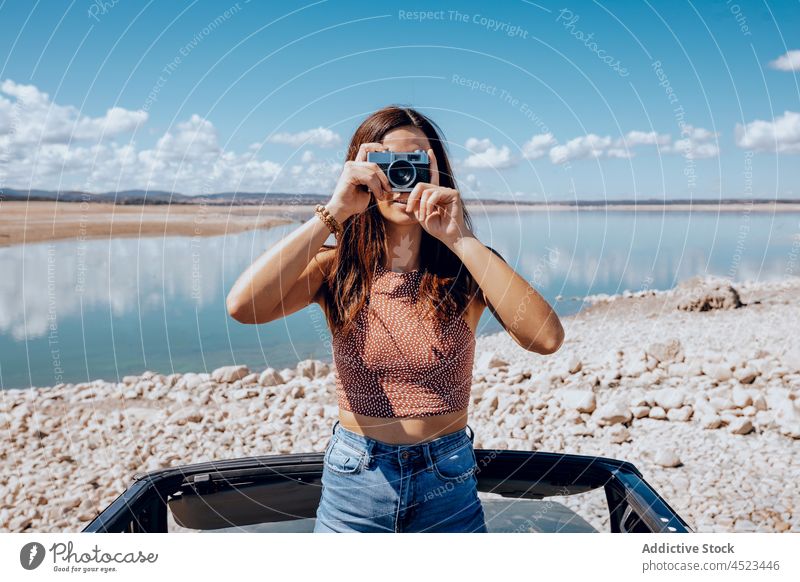 Young woman taking photo on vintage camera photo camera take photo capture car coast old fashioned pond nature female transport environment lake old timer