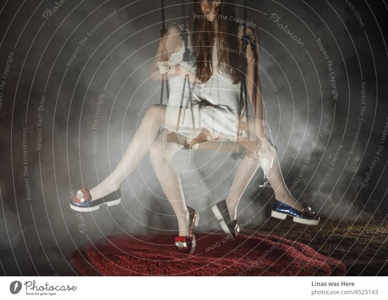 A double exposure image of a young brunette girl wearing a sexy white dress. Her fancy shiny shoes also caught the attention. Some kind of smoke or fog in the image creates a moody atmosphere.