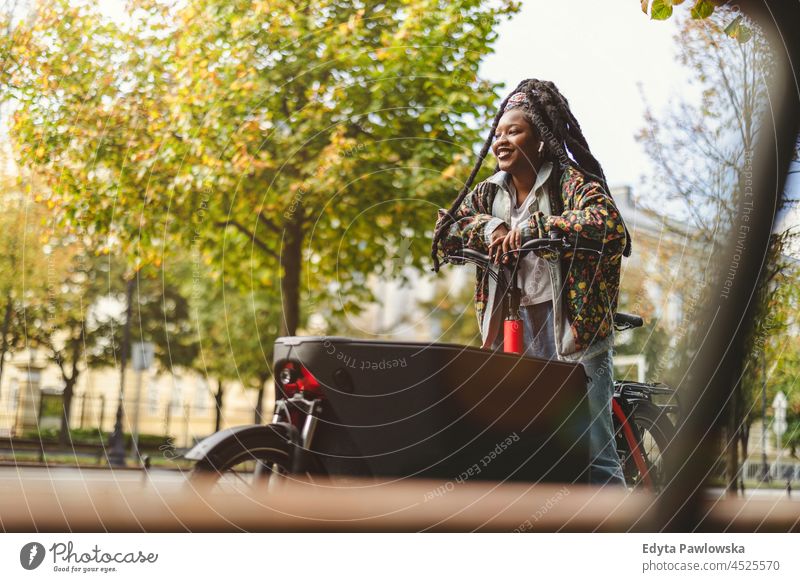 Woman using cargo bike in urban area unaltered natural real people authentic body inclusivity body positive one person hipster girl hairstyle dreadlocks