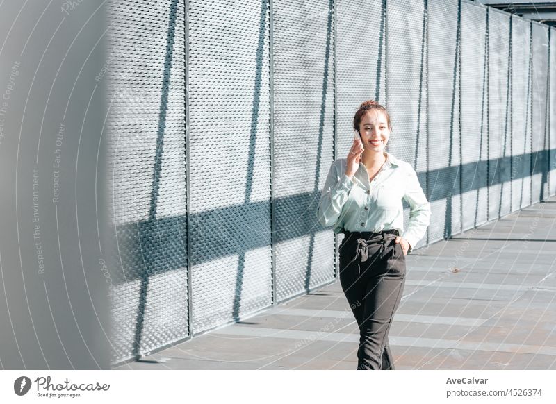 Young arab woman entrepreneur woman smiling,doing phone calls while looking worried at, outdoors. Looking to the right with Copy space, Business concept, portrait of office