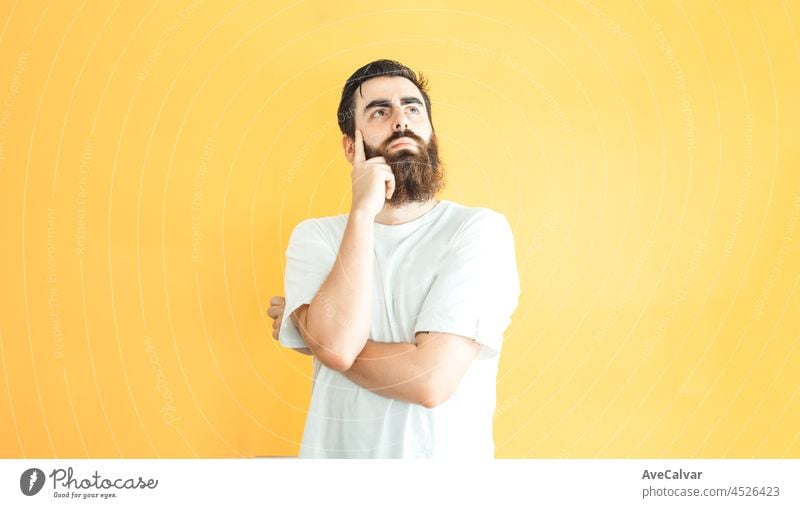 Young hipster bearded man serious thinking position, blank space, copy space, soft yellow removable background, minimal basic, ad concept deal, white shirt space