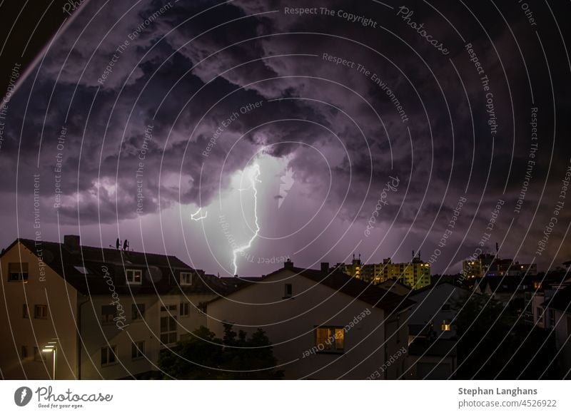 Image of lightning strike over buildings with threatening cloud formations nature thunderstorm sky electricity energy weather power flash rain danger bolt night