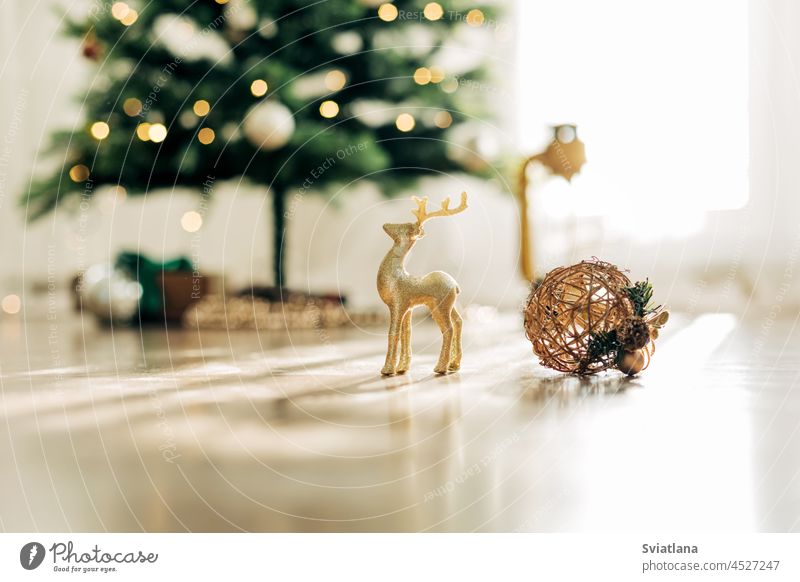 Golden deer and Christmas ball on the background of the Christmas tree, details of decorations. Christmas still life, winter composition christmas reindeer gold