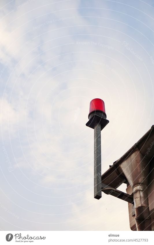 red warning light at the corner of a building next to the gutter / alarm system / protective measure Warning light house corner Alarm signal lamp Sky