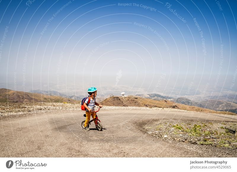 Small boy riding uphill on his first bicycle in Sierra Nevada mountains, Spain child sierra nevada sport spain hike altitude endurance top standing fun