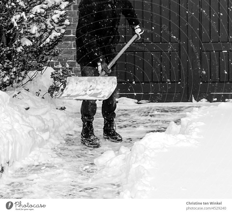 A man clears snow from in front of his garage as it continues to snow Man Snow Shoveling snow shovelling shovel snow clear snow Virgin snow Winter White Cold