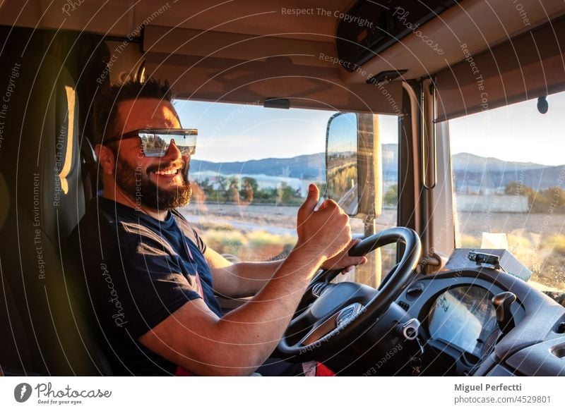 Heavy truck driver happy to be able to drive a truck, and making the gesture of OK, with the thumb up. steering wheel working sunset driving transport men