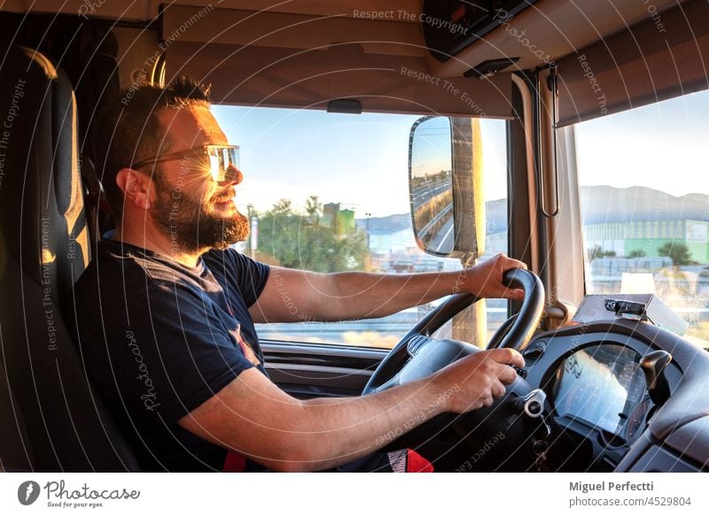 Truck driver with both hands holding the steering wheel and the sun facing forward. truck driver working happy sunset driving transport men blissful worker