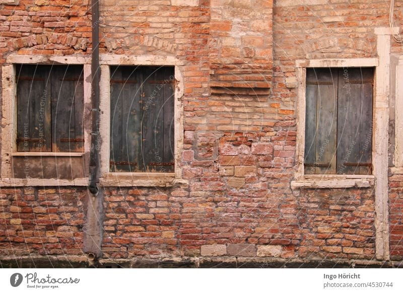 Reddish ancient brick wall with three windows closed by pale blue shutters. Irregular brickwork. Wall (barrier) Shutter bricks Brick red Brick wall Facade Old
