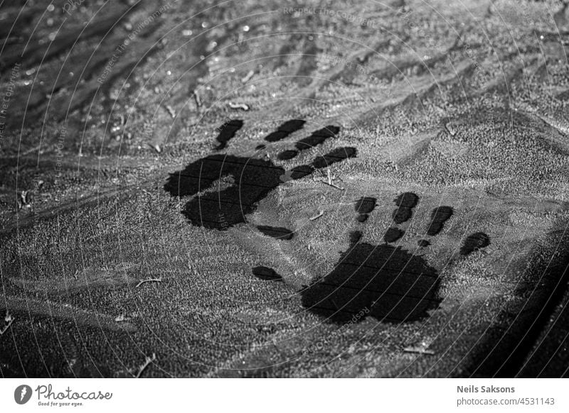 Palm print on the frozen glass. Trace hands and fingers on the car window covered with snow frost abstract art autumn backdrop background blue closeup cold