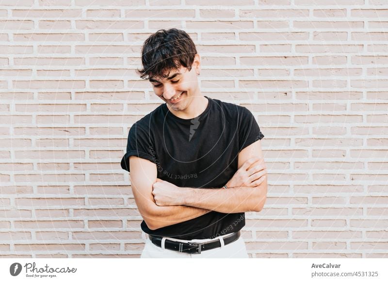 Young urbanite man with black tshirt laughing while being portrayed, confident and happy, new job applicant, looking towards the future with happiness, copy space, lgbt