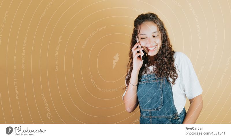 Young mixed race woman holding attending a call and smiling, yellow background removable background, minimal image, copy space, basic situations and feelings expressions