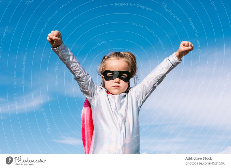 Brave kid in superhero costume showing fists girl child strong power courage pretend fearless gesture blue sky hill cape brave childhood strength protect cloak