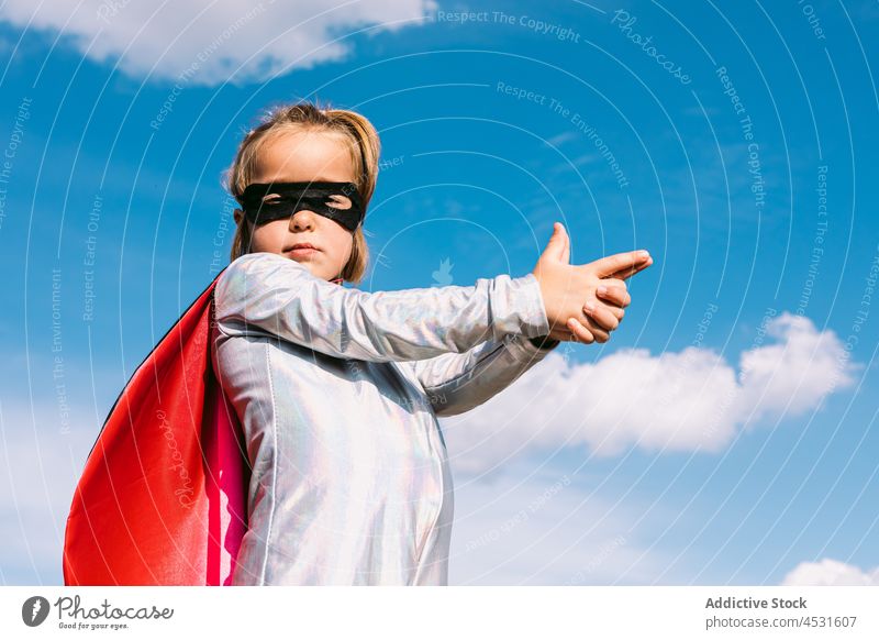 Fearless girl in superhero costume showing shoot gesture courage confident pretend protect brave child mask kid rescue fantasy danger imagination gun save