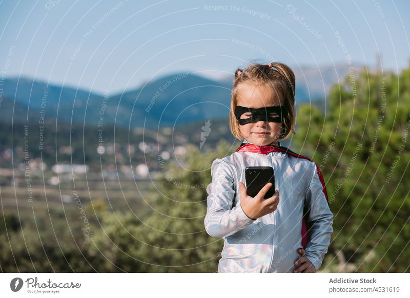 Brave girl in superhero costume browsing on smartphone child brave using text message pretend courage power self assured confident kid self confident listen