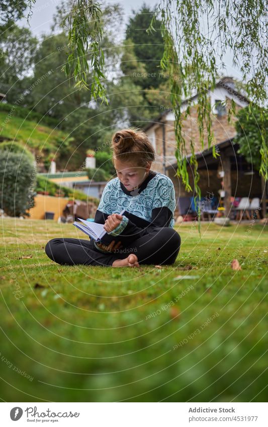 Girl reading book on lawn girl kid countryside literature childhood pastime hobby backyard free time residential courtyard barefoot house focus bookworm rest