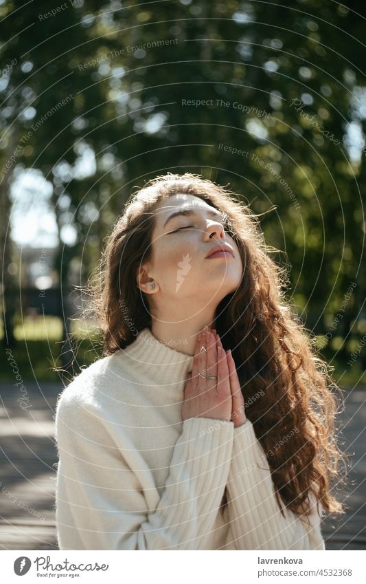 Young brunette woman meditating outdoors with her eyes closed wellbeing wellness fitness namaste pose active relaxation asana practicing healthy training