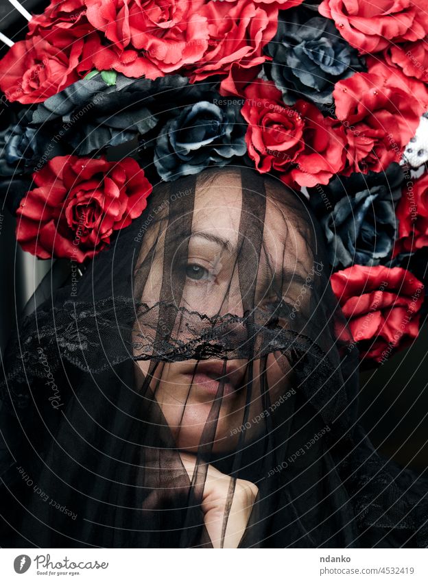 a woman of Caucasian appearance is dressed in a black veil and a large wreath of red-black roses beauty flower beautiful hair portrait female fashion art model
