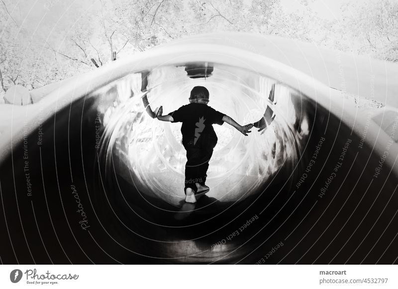 Child in a slide Slide tube metal tube mirroring Steep smooth Playground Infancy Back standing Large Joy Climbing happy childhood black and white