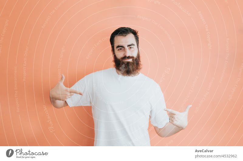 Young hipster bearded man looking away from camera, copy space, soft orange removable background, minimal basic, ad concept deal, white shirt space male