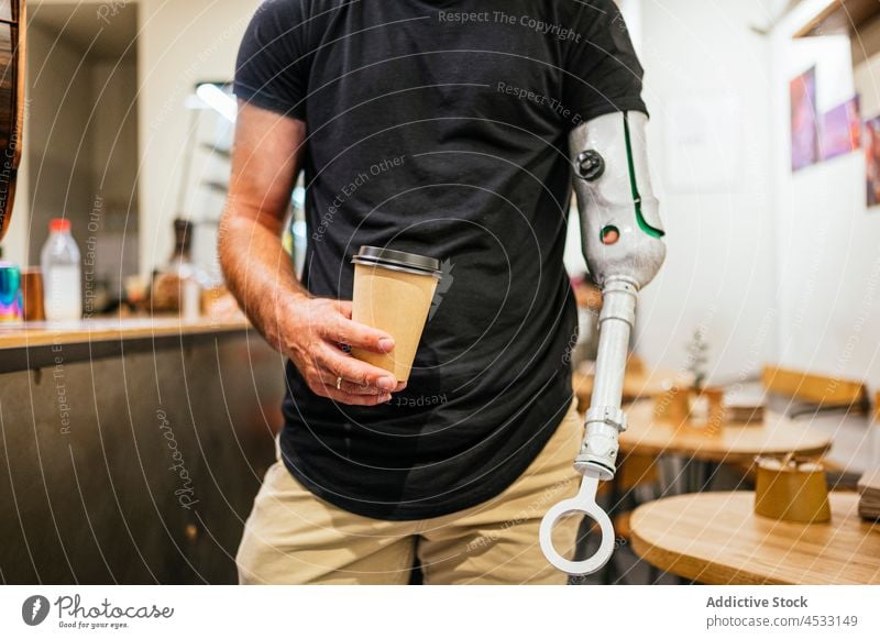 Crop man with artificial limb with cup of coffee prosthesis bionic arm cafe amputee male takeaway handicap beverage paper cup drink to go disable modern