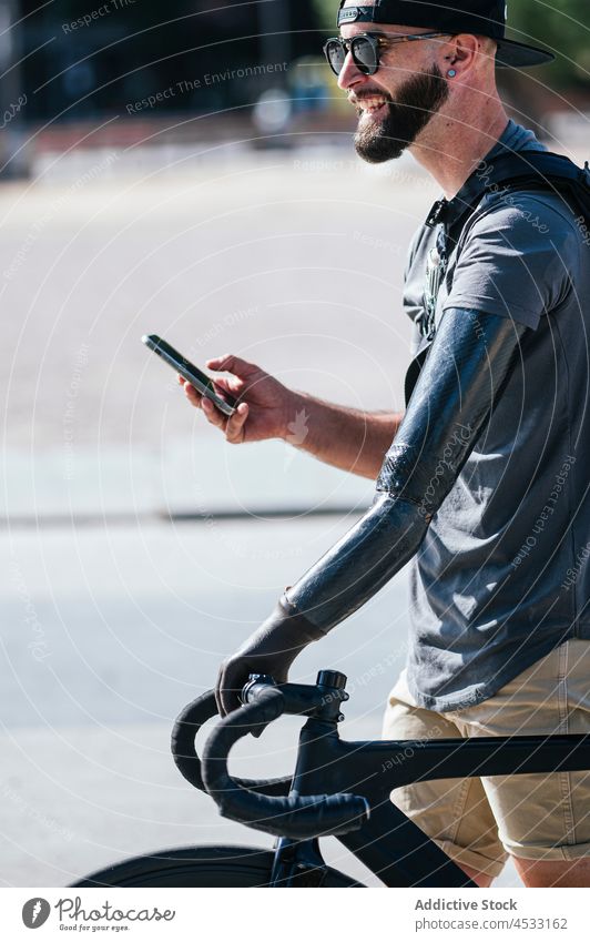 Smiling man with prosthetic arm browsing on smartphone prosthesis artificial smile limb amputee male handicap device happy walk cheerful bike street gadget