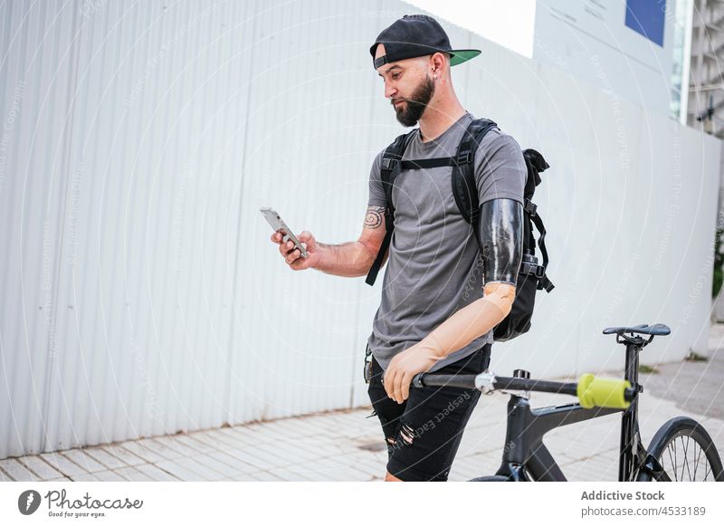 Man with prosthetic arm browsing on smartphone man prosthesis artificial limb amputee male handicap device happy stand bike street gadget mobile bicycle
