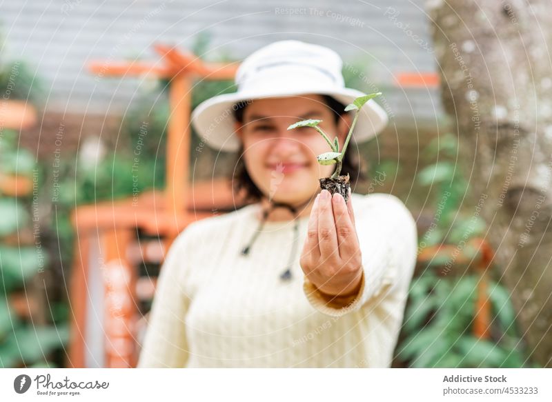 Smiling woman showing sprout in garden gardener seeding stem plant agriculture cultivate positive female farm botany grow smile work countryside farmer growth