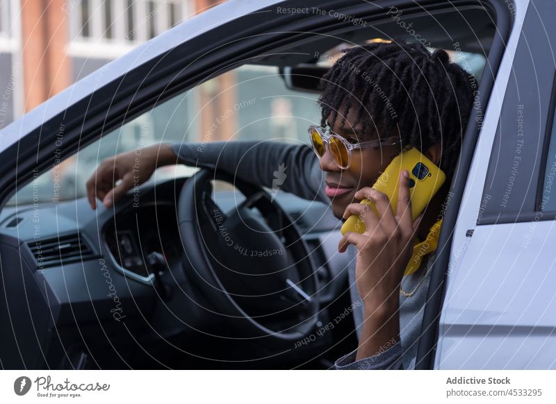 Black male driver talking on smartphone in car man open using street style cool phone call communicate connection device headphones sunglasses transport listen