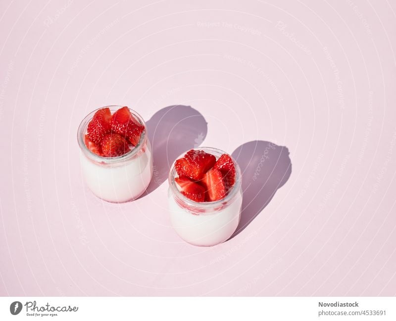 two glasses with natural yogurt and fresh strawberries isolated on light pink background, with copy space strawberry milk fruit two studio indoors healthy diet