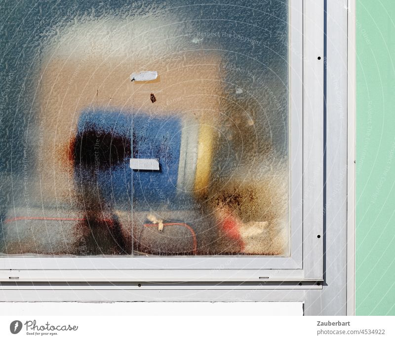 View into a window with an aluminium frame made of frosted glass, behind it various objects Window Frosted glass Aluminium Aluminium frame Green Blue Bag ton