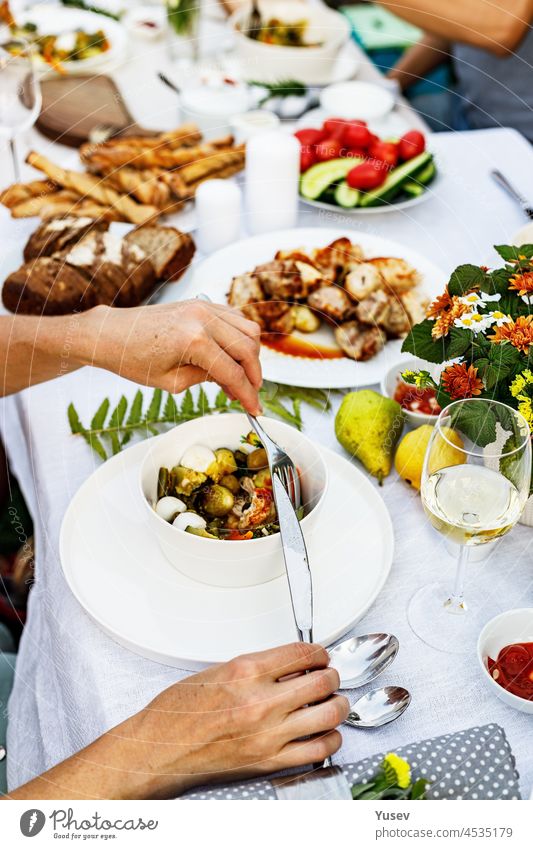 A festive family dinner or barbecue in the summer garden. Family leisure and celebration and food concept. People are eating at a garden party. BBQ, vegetables, wine and snacks. Life in the suburbs
