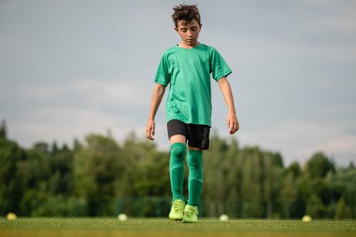 Young football player in sportswear walks thoughtfully on football field Boy (child) Foot ball Football pitch Soccer training soccer field Football boots