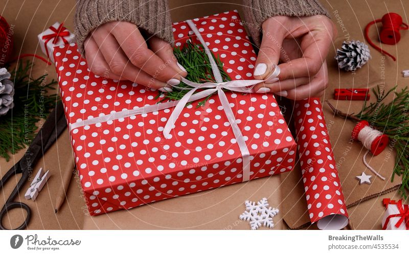 Woman packing Christmas gifts with red paper Gift woman brown brown paper giftbox wrap hands white Caucasian natural holiday festive preparation prepare twine