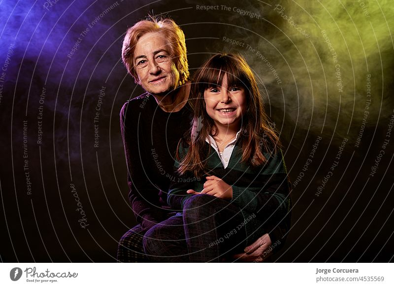 genarcional gap in family portrait between grandmother and granddaughter. portrait in original studio. grandparent elderly portrayal 70s happiness juvenile