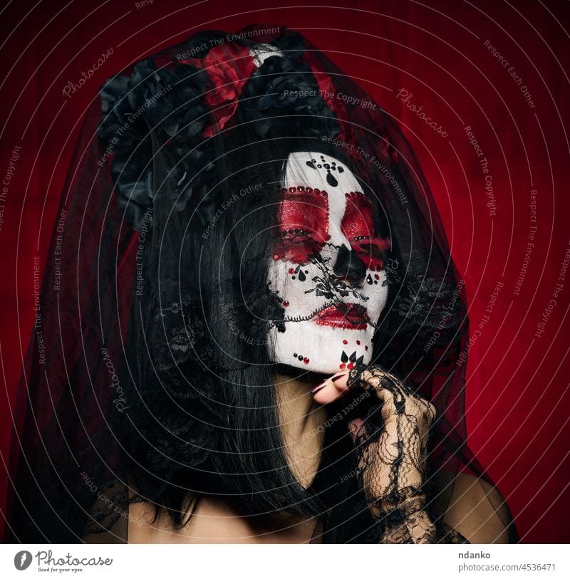 beautiful woman with a sugar skull makeup with a wreath of flowers on her head, red background halloween horror beauty female portrait costume death dead