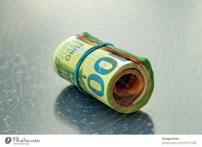 Euro money roll on a dark table. 100 and 50 euro notes rolled into a roll and tied together with a rubber band. Rolled up Euro notes accounting background Bench