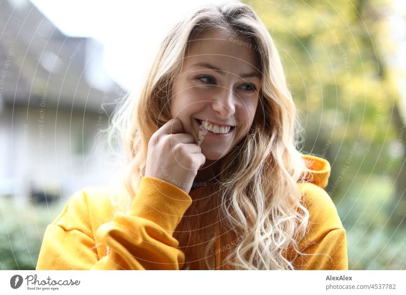 Portrait of young slim smiling woman with long blond hair and yellow hoodie on balcony in autumn Woman Young woman Large Blonde Long-haired pretty daintily Slim